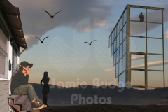 © Jamie Budge, all rights reserved.
CELL PHONE KID ON HOME STAIRS BRIDGES DISTANCE TO SURREAL OFFICE WITH SEAGULL SKY WITH  MOM AND DAD IN SILHOUETTE. No Rights Implied by possession of this image.     Contact:
Jamie Budge (310) 453-4808  jamiebudge@windskate.com