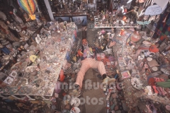 © Jamie Budge, all rights reserved.
"CLUTTER KING" GARY FISHER,  SURROUNDED A HELTER SKELTER ARRAY OF TRINKETS, LAYS IN THE "AISLE" OF HIS  LIVING ROOM.   No Rights Implied by possession of this image.     Contact:
Jamie Budge (310) 453-4808  jamiebudge@windskate.com